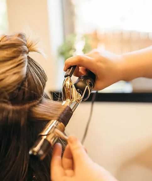 Stylist curling a client's hair in a salon.